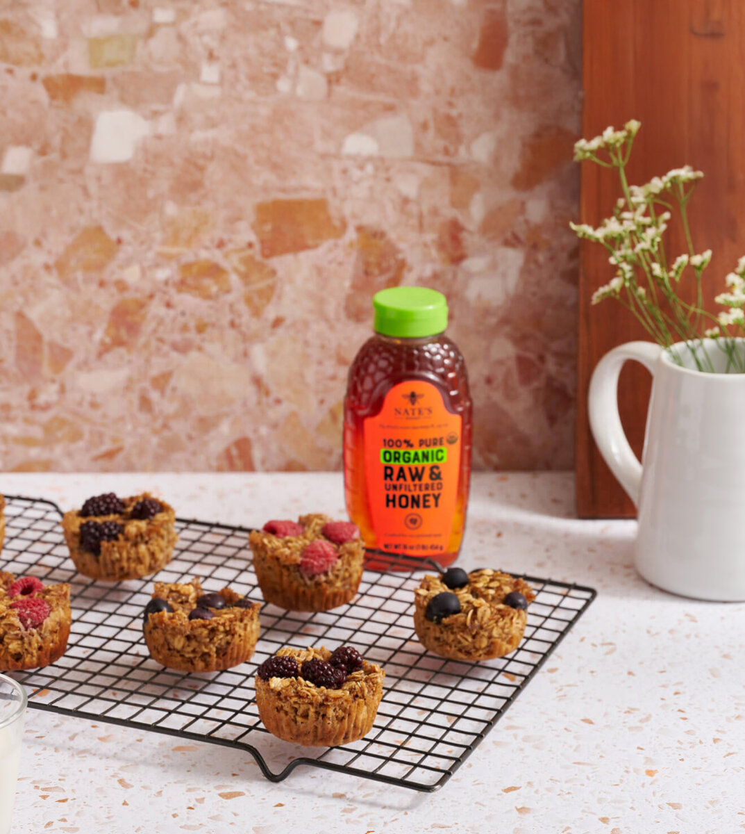 Oatmeal cups on cooling rack next to bottle of organic honey.