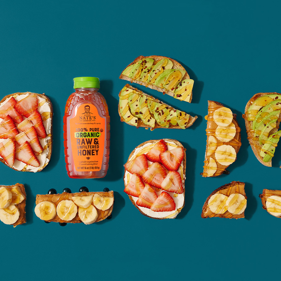 Nate's Organic Honey with fruit-topped toast on a teal background.