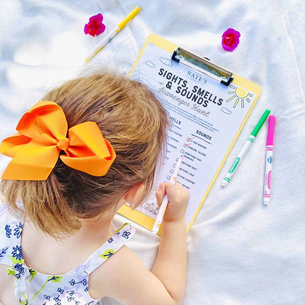 A child with a bow in her hair is writing on a Sights, Smells, & Sounds of Spring worksheet by Nature Nate's.