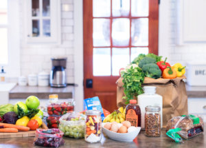 Fresh groceries arrayed on a kitchen island, with a door and windows behind.