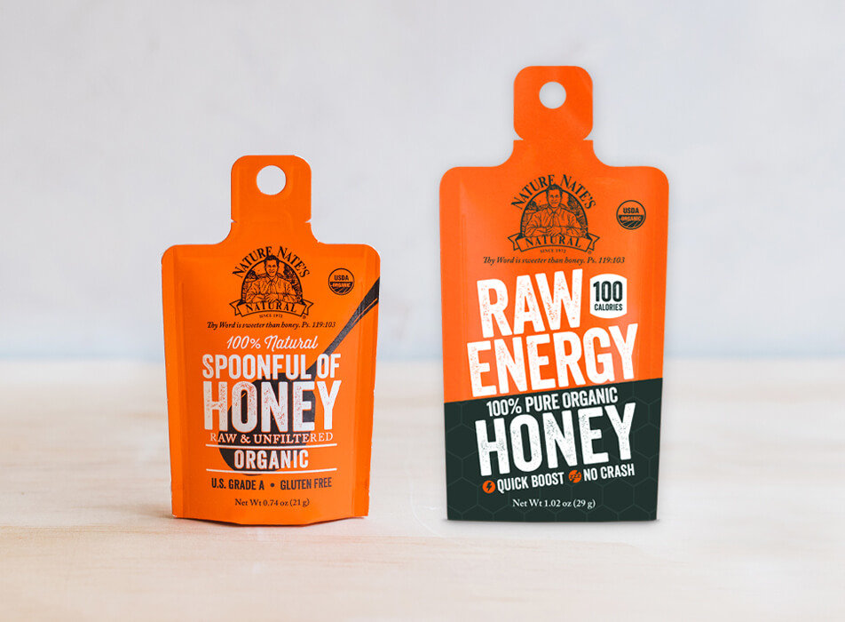 Two small Nate's honey containers with SPOONFUL OF HONEY and RAW ENERGY HONEY labels, standing against a plain background.