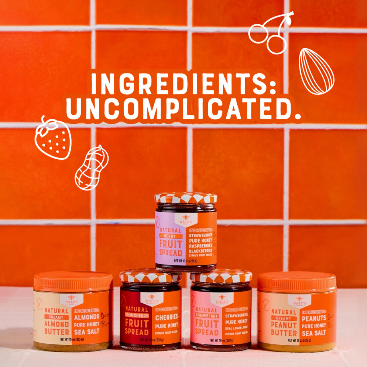 Jars of Nate’s Honey Fruit Spreads and Nut Butters arranged in front of an orange tile background with the text “Ingredients: Uncomplicated.” and simple line‑art illustrations of fruit and nuts.