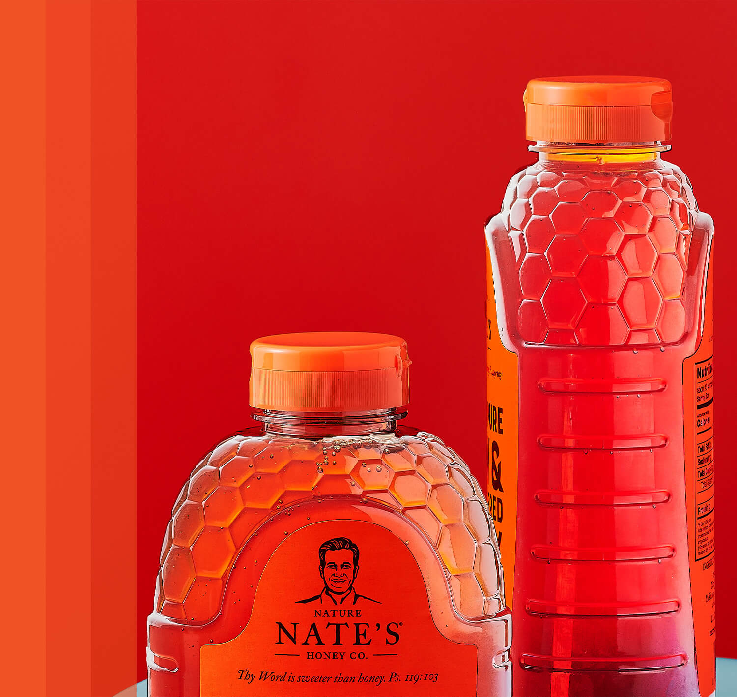 Two Nature Nate's honey bottles with honeycomb designs on a red background.