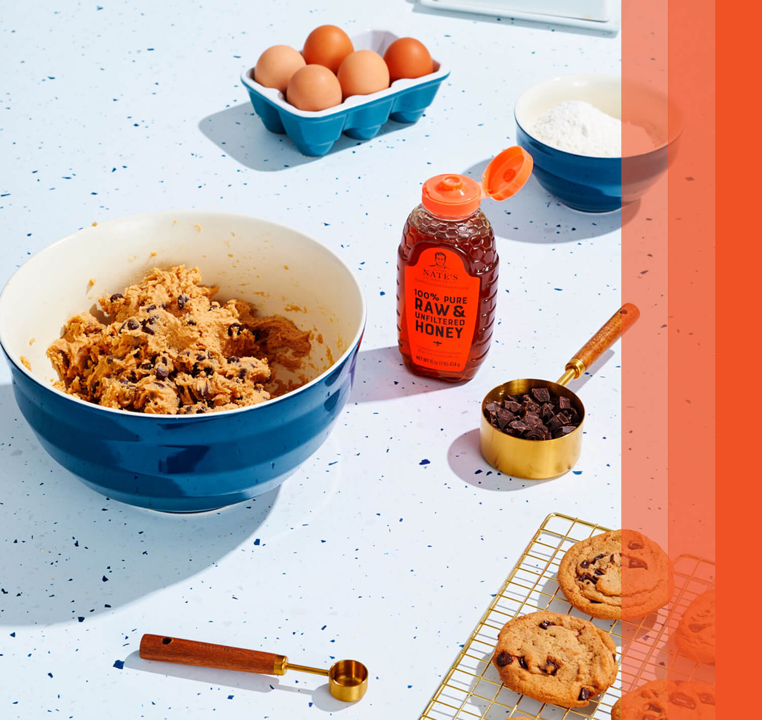 Baking setup with cookie dough, chocolate chips, and Nature Nate's honey bottle.