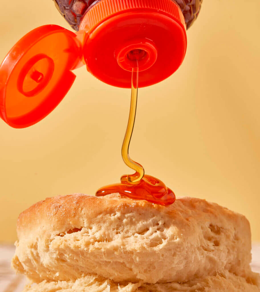 Nate’s honey drizzling onto a biscuit from a squeeze bottle.