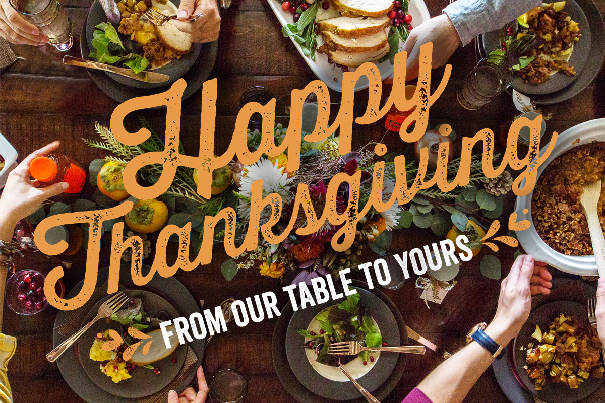 Thanksgiving table spread with festive Happy Thanksgiving From Our Table to Yours text overlay.