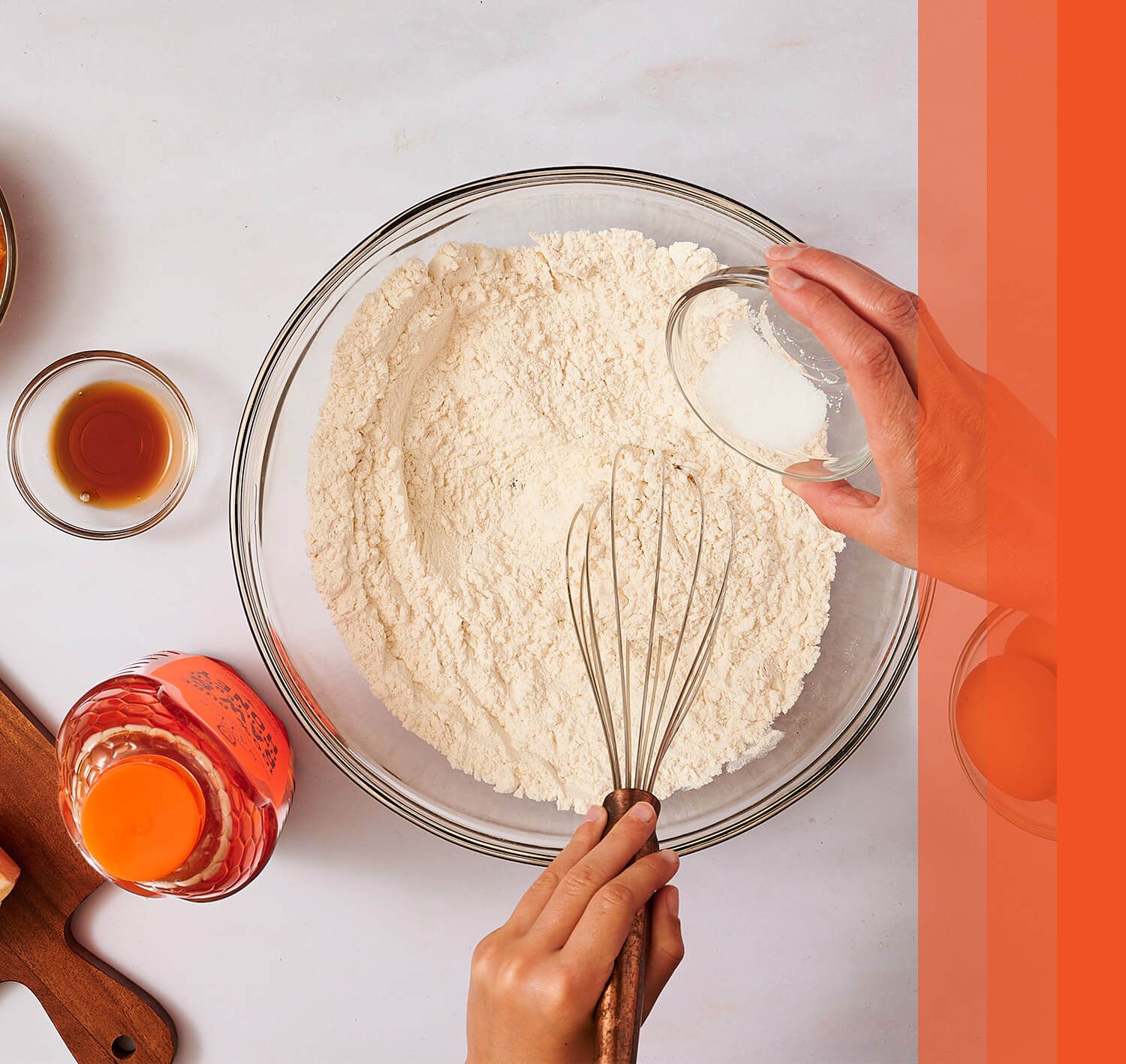 Hands whisking flour with Nature Nate's honey and baking ingredients nearby.