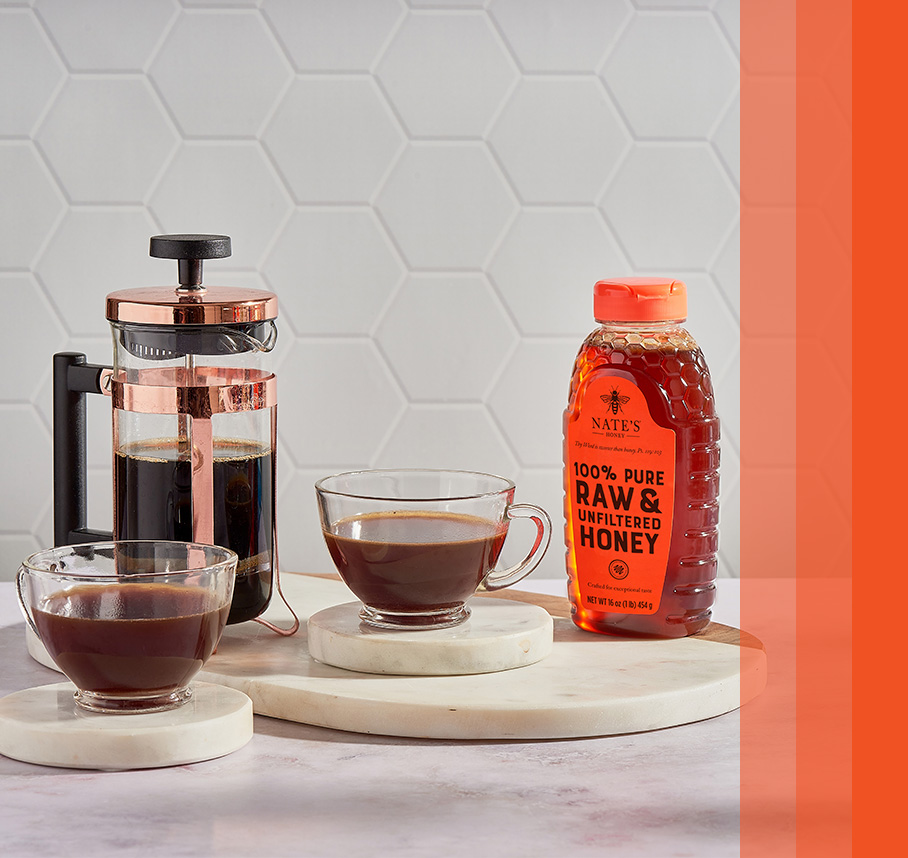 Nate’s honey bottle on counter with coffee press and cups of coffee.