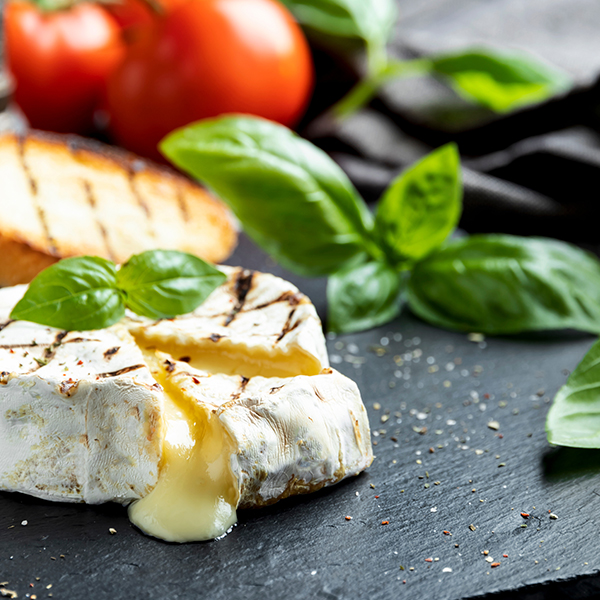 brie, basil, bread and tomatoes on black table