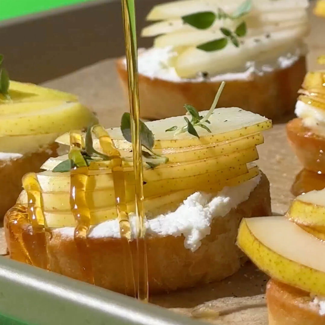 honey pouring on top of mini pear crostinis