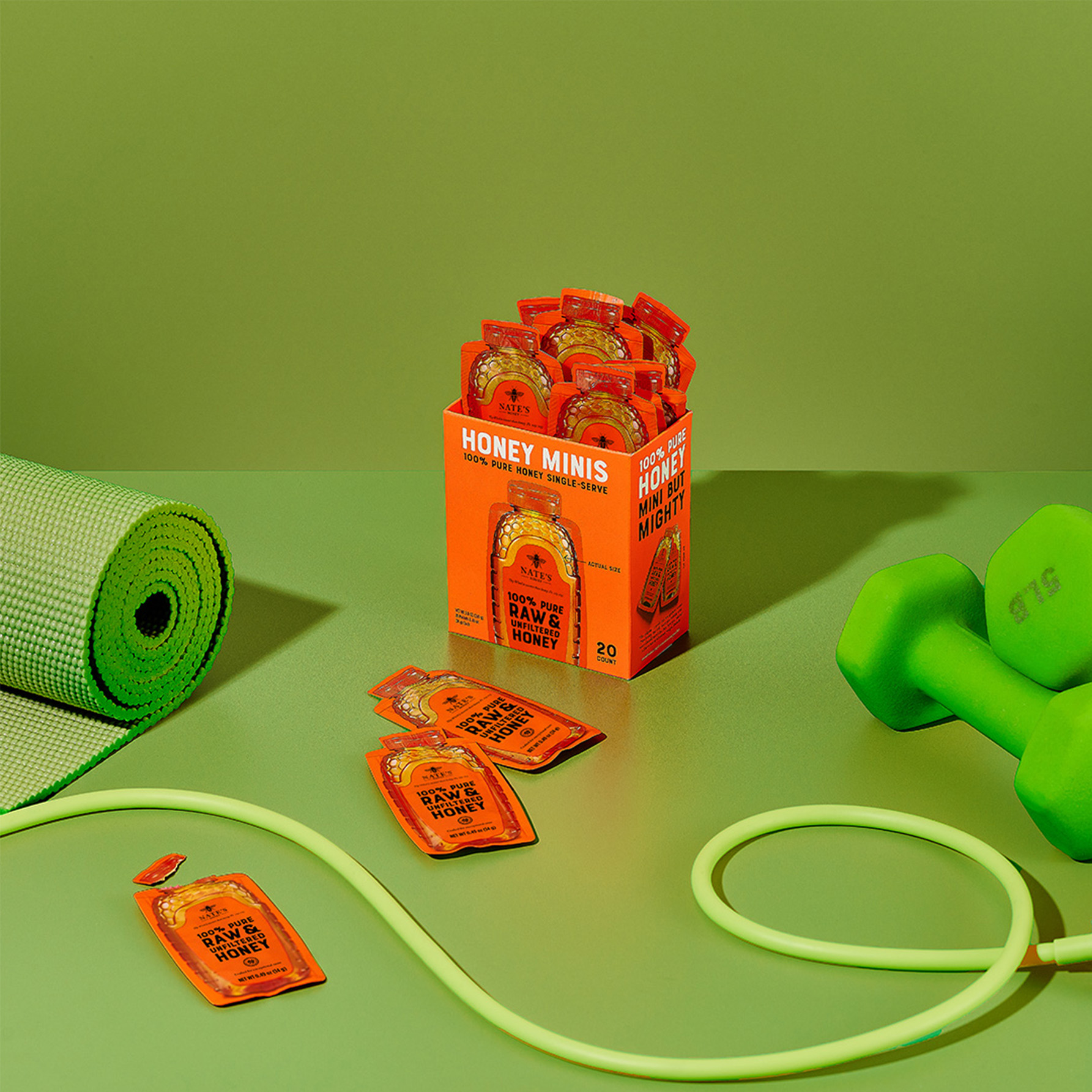 Box of Nate’s Honey Minis surrounded by workout essentials like a yoga mat, dumbbells, and jump rope.