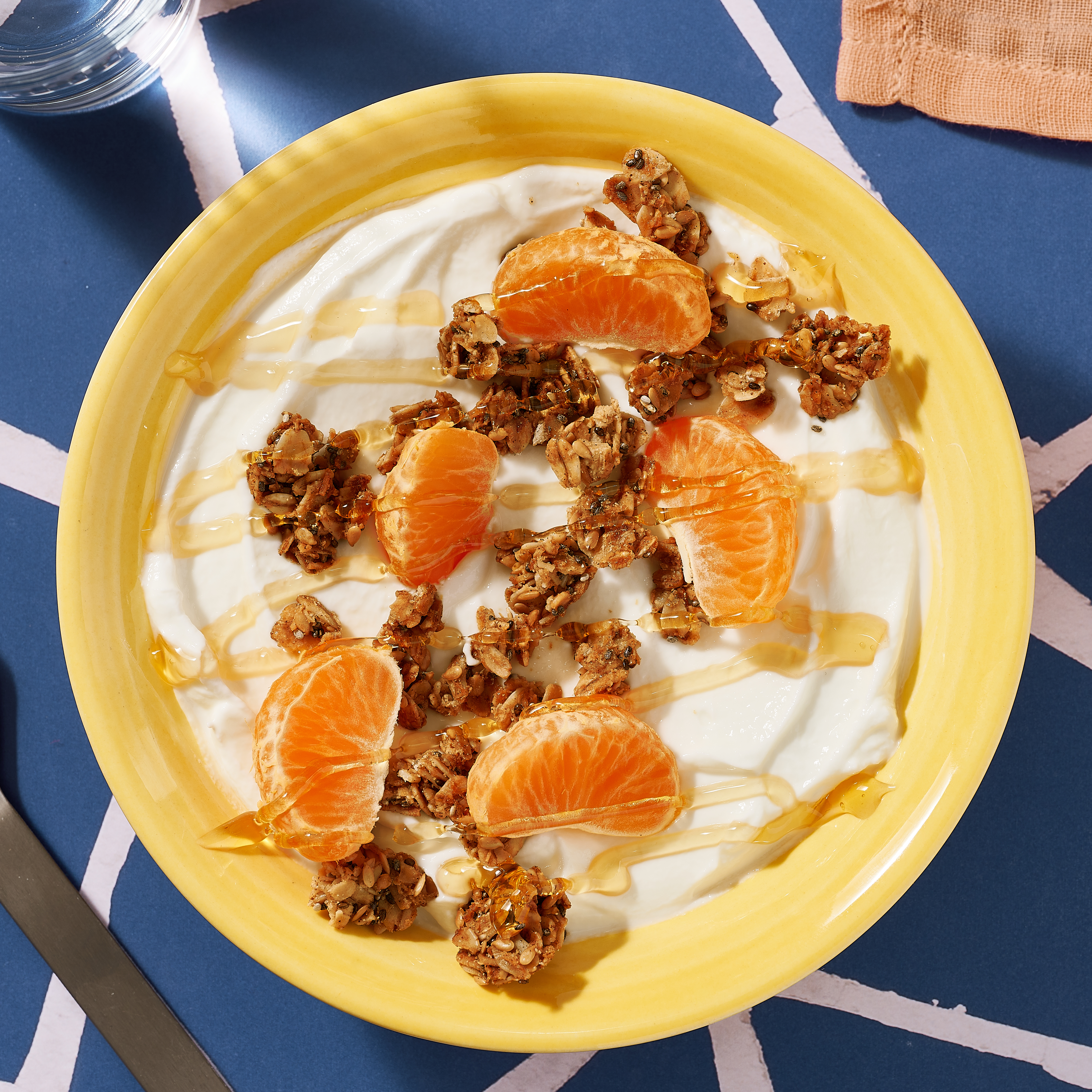 Yellow bowl of clementine coconut yogurt with honey drizzle.