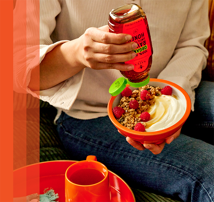 Drizzling Nate’s Organic Raw & Unfiltered Honey over yogurt topped with granola and fresh berries.