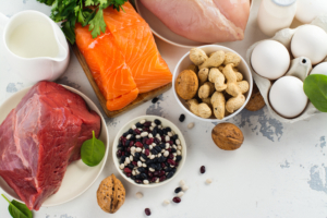 Various proteins like meats, fish, nuts, and eggs on a table.
