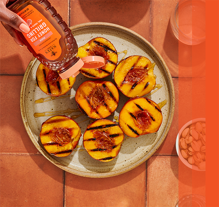 Grilled peached being drizzled with peach honey.