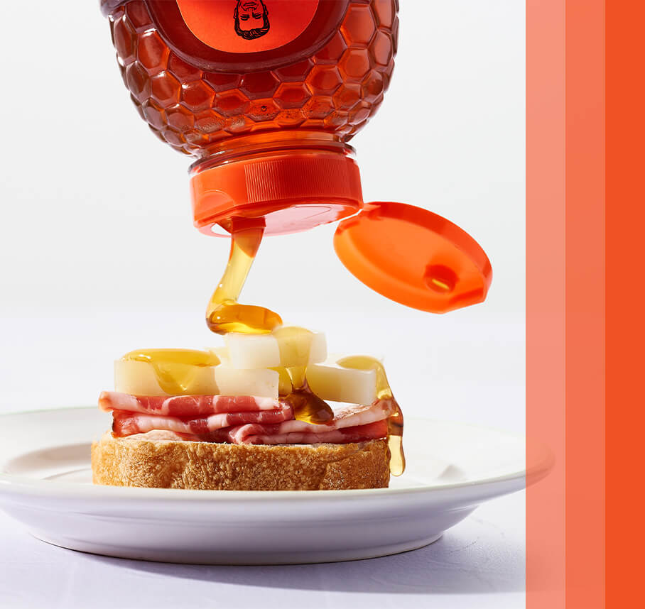 Miel rociada sobre tostadas de carne y queso en un plato blanco