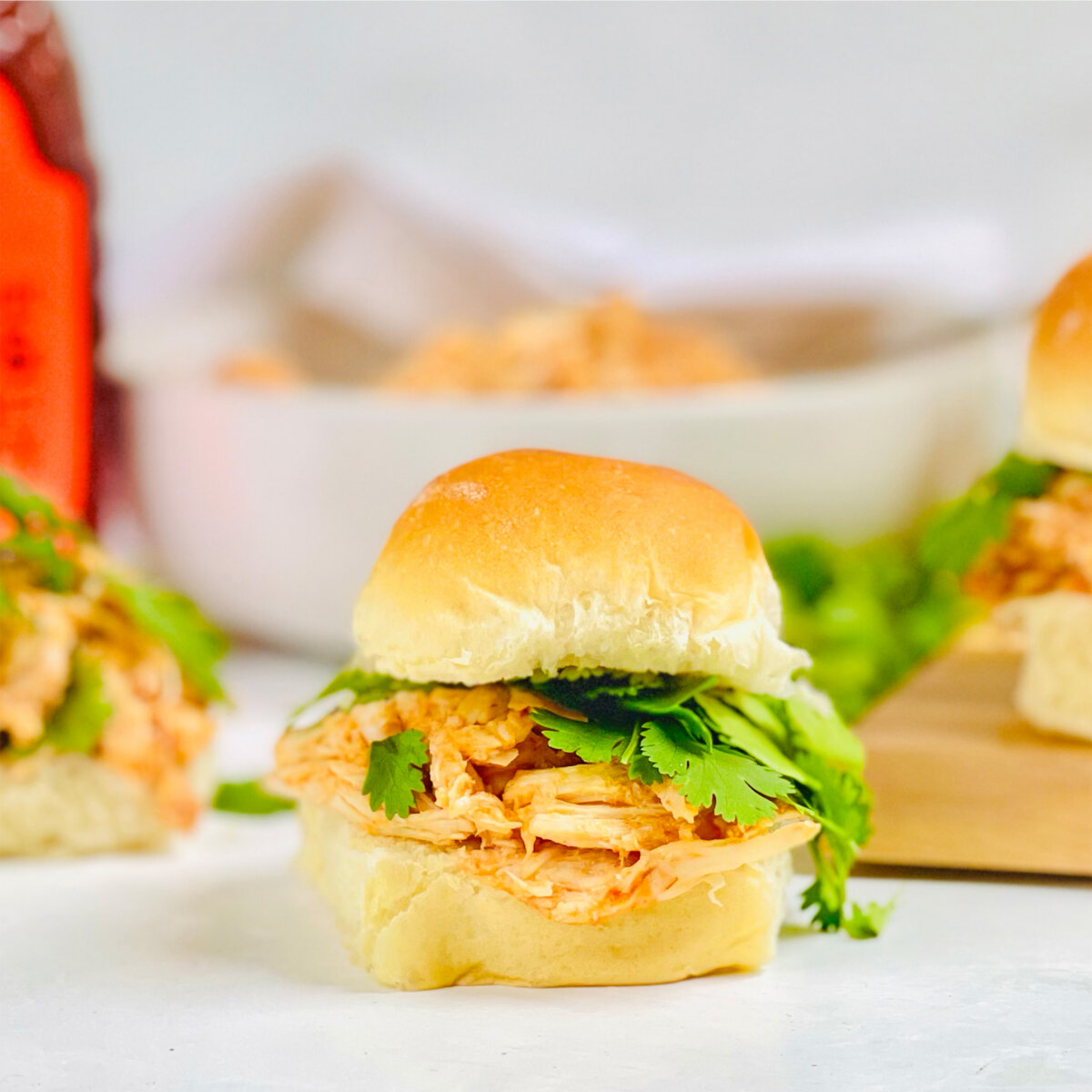 Chicken sliders with cilantro on a board, Nate's Honey bottle in the back.