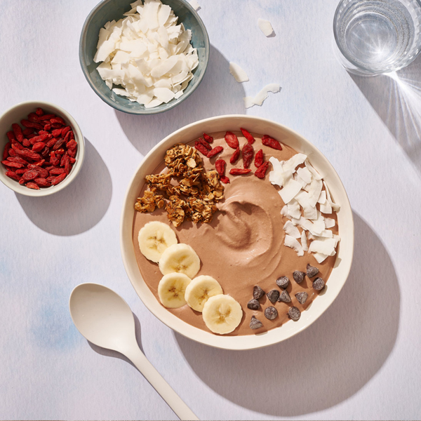 Smoothie Bowl on white background next to bowls of ingredients and white spoon