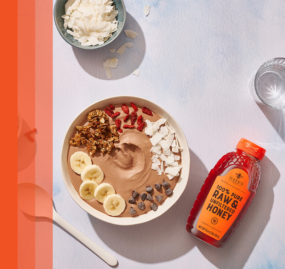 Smoothie bowl with toppings and Nature Nate’s honey bottle.