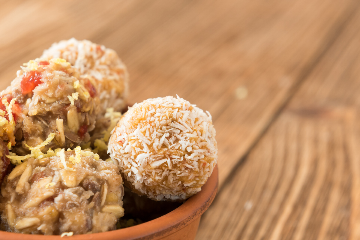 Energy bites in a bowl, sprinkled with coconut; a wholesome, homemade snack on wooden background.